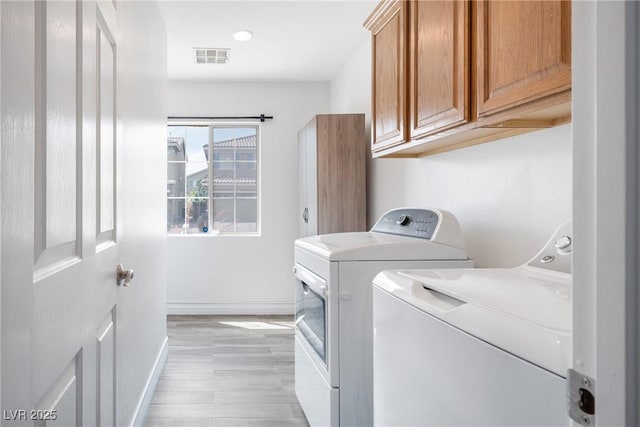 laundry room with washer and dryer, cabinet space, baseboards, and light wood finished floors