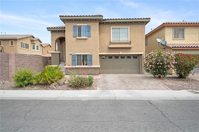 view of front of house featuring decorative driveway, stucco siding, a garage, fence, and a tiled roof