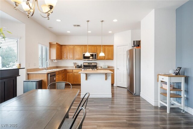 kitchen featuring appliances with stainless steel finishes, light countertops, a sink, a center island, and recessed lighting
