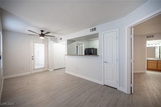 5055 W Hacienda Ave Unit 1097, Las Vegas, NV 89118 - unfurnished living room featuring light wood-style flooring, a ceiling fan, and baseboards