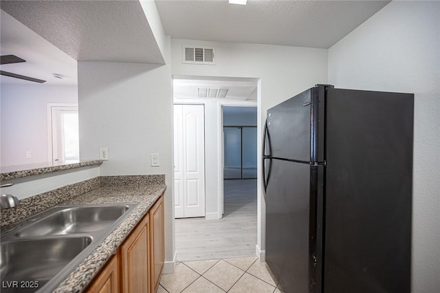 5055 W Hacienda Ave Unit 1097, Las Vegas, NV 89118 - kitchen featuring freestanding refrigerator, a sink, brown cabinetry, and light tile patterned flooring