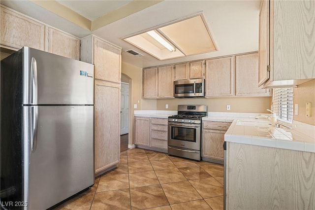 4517 Rodman Dr, Las Vegas, NV 89130 - kitchen with appliances with stainless steel finishes, tile countertops, light brown cabinetry, and a sink