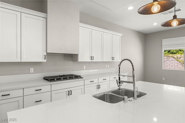 kitchen featuring a sink, stainless steel gas cooktop, light countertops, white cabinetry, and recessed lighting