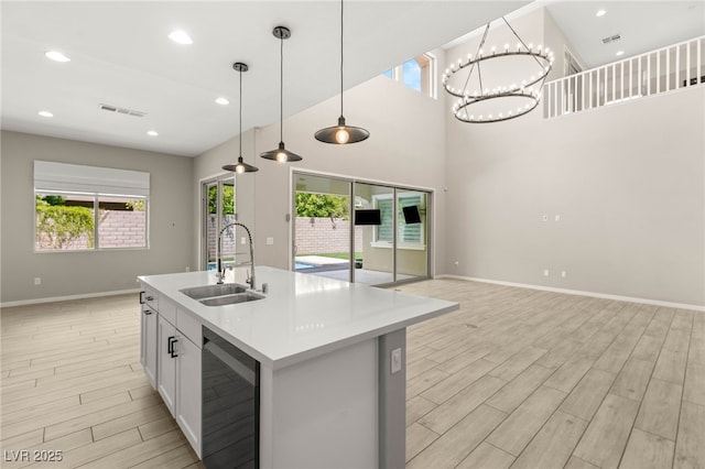 kitchen with a sink, light wood-style floors, baseboards, light countertops, and hanging light fixtures
