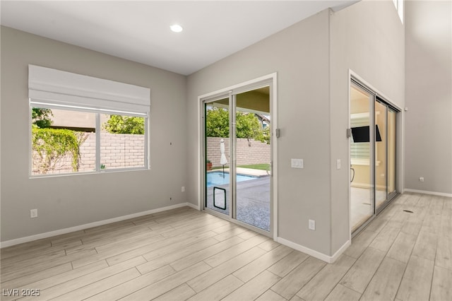 spare room featuring light wood finished floors, baseboards, and recessed lighting