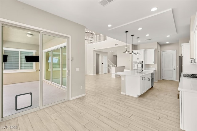 kitchen featuring a chandelier, an island with sink, a sink, light countertops, and stainless steel gas cooktop