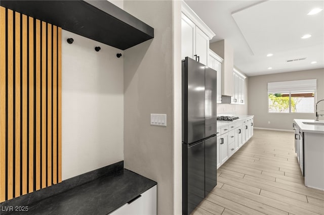 kitchen with stainless steel appliances, light wood-style flooring, a sink, white cabinetry, and recessed lighting