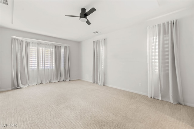 carpeted spare room featuring ceiling fan and baseboards