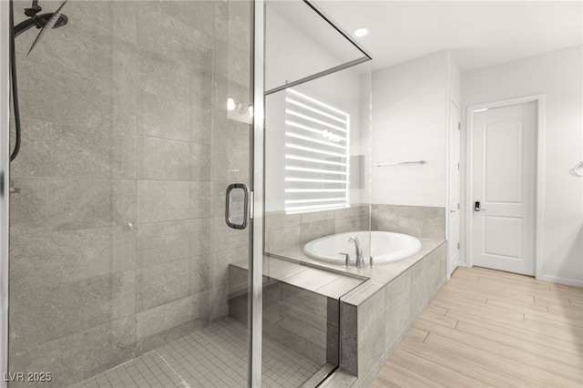 bathroom featuring a garden tub, a shower stall, and wood finished floors