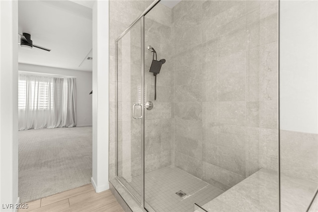 full bathroom with a shower stall, ceiling fan, and wood finished floors