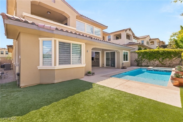 rear view of property with an in-ground hot tub, a patio, central AC unit, stucco siding, and a tile roof