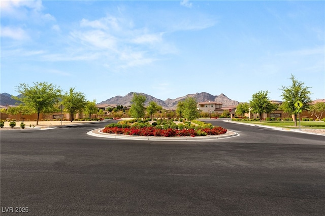 view of asphalt road featuring curbs, a residential view, a mountain view, and sidewalks