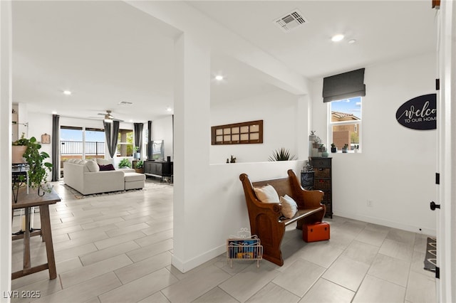 sitting room with plenty of natural light, recessed lighting, and baseboards