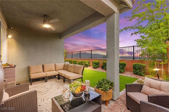 patio terrace at dusk featuring outdoor lounge area, ceiling fan, and a fenced backyard