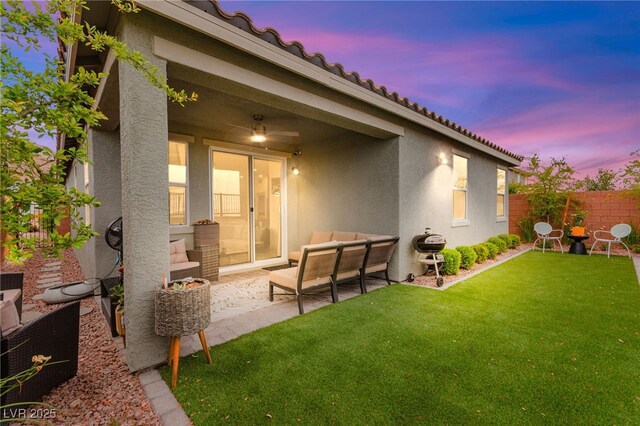 back of house at dusk featuring stucco siding, outdoor lounge area, a patio, and a tile roof