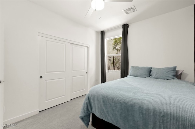 bedroom with light colored carpet, a closet, ceiling fan, and baseboards