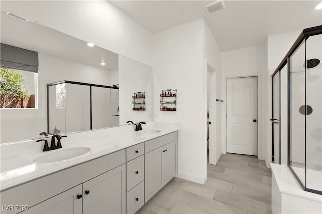 full bathroom with a stall shower, double vanity, baseboards, and recessed lighting