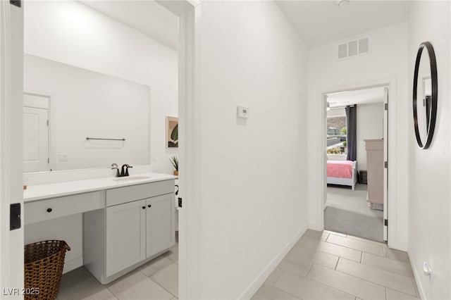 ensuite bathroom featuring vanity, baseboards, and tile patterned floors