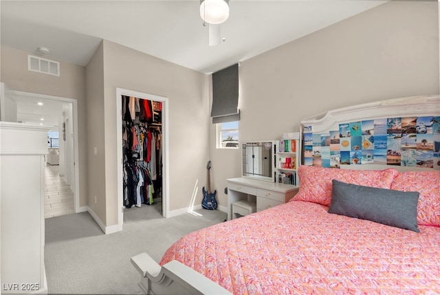 bedroom featuring light carpet, baseboards, a spacious closet, a closet, and ceiling fan