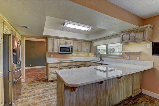 893 Fairway Dr, Boulder City, NV 89005 - kitchen with stainless steel appliances, a peninsula, a textured ceiling, a sink, and light wood finished floors