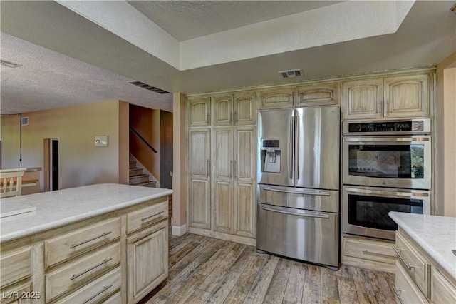 893 Fairway Dr, Boulder City, NV 89005 - kitchen featuring stainless steel appliances, light countertops, light wood finished floors, a textured ceiling, and light brown cabinetry