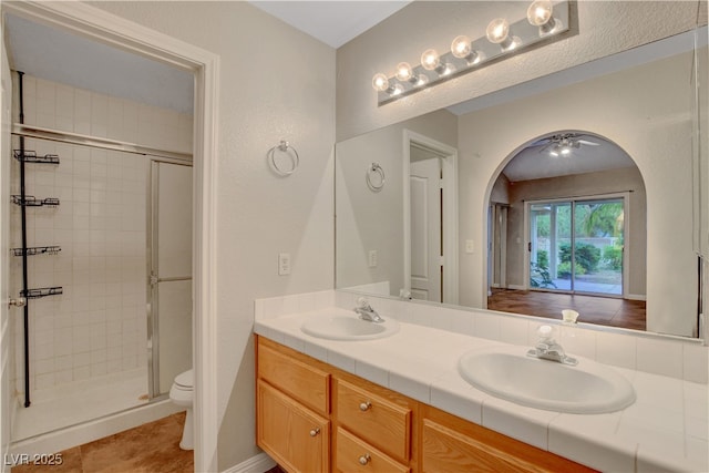 full bath featuring toilet, a stall shower, double vanity, and tile patterned flooring