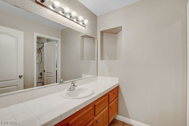 full bathroom with a shower, vanity, and baseboards