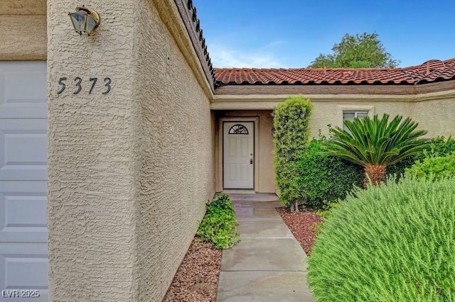 property entrance featuring a tiled roof and stucco siding