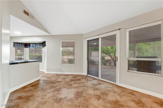 empty room featuring baseboards and lofted ceiling