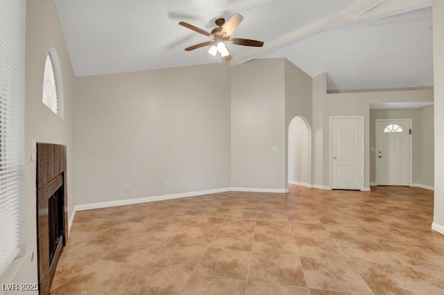 unfurnished living room with a ceiling fan, a fireplace, healthy amount of natural light, high vaulted ceiling, and arched walkways