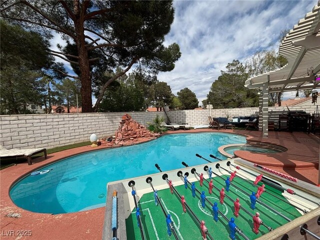 view of swimming pool featuring a fenced backyard and a pool with connected hot tub
