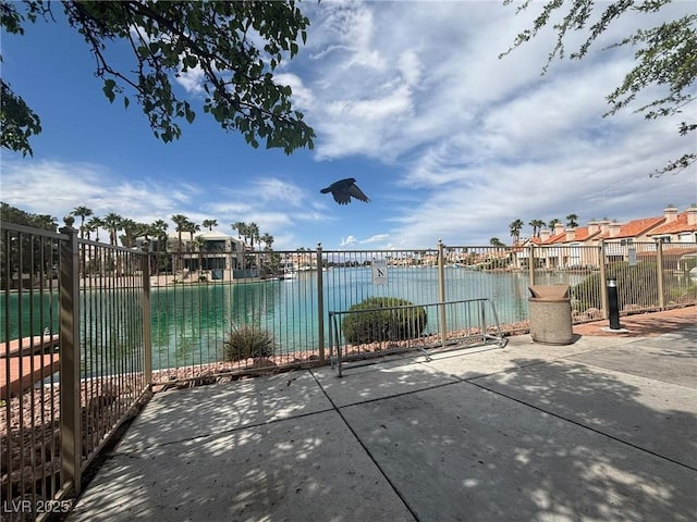 view of patio / terrace featuring a water view and fence