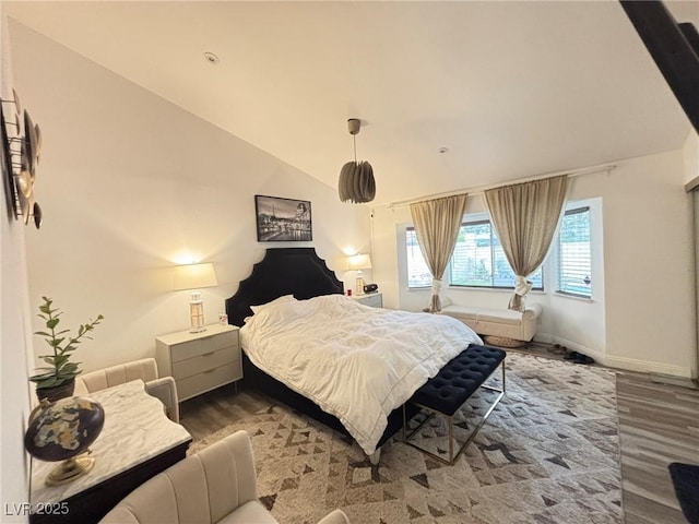 bedroom with wood finished floors, lofted ceiling, and baseboards