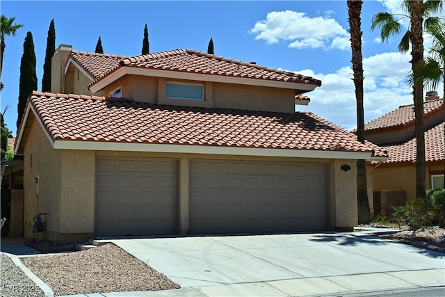 mediterranean / spanish-style home with concrete driveway, stucco siding, a tile roof, and an attached garage