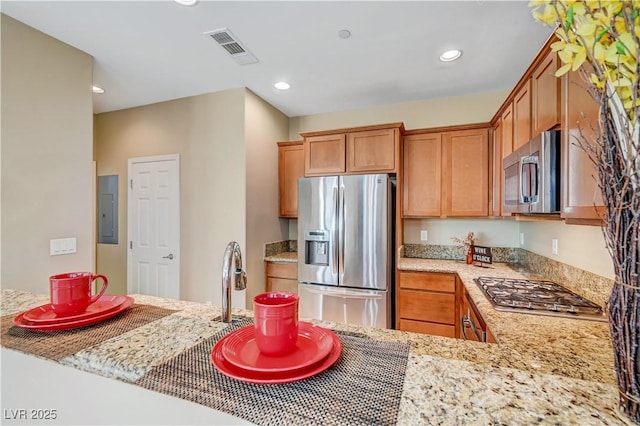 11420 Ogden Mills Dr Unit 101, Las Vegas, NV 89135 - kitchen featuring stainless steel appliances, electric panel, recessed lighting, light stone counters, and brown cabinetry