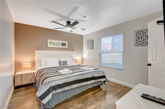 bedroom with light wood-style flooring, baseboards, and ceiling fan