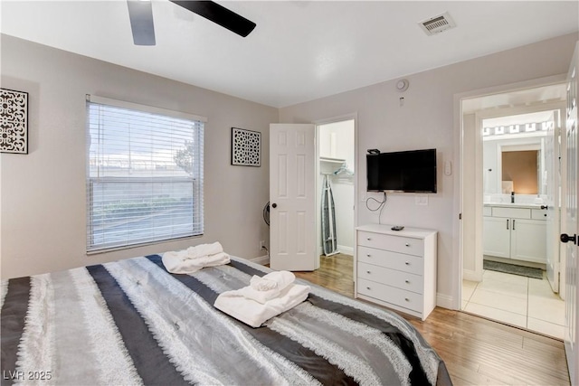 bedroom with light wood-type flooring, baseboards, connected bathroom, and a ceiling fan