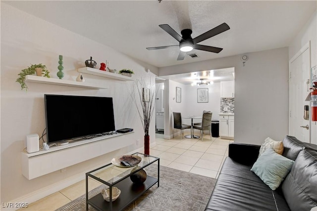living room featuring light tile patterned floors, ceiling fan, and baseboards