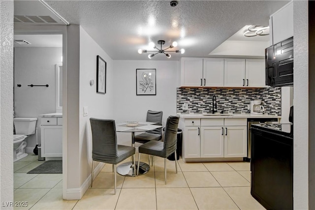 kitchen with a sink, light countertops, range, light tile patterned floors, and decorative backsplash