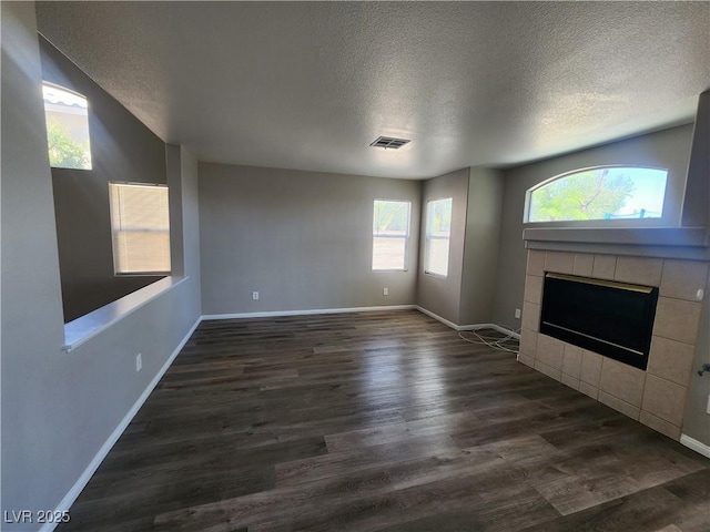 10400 Beachwalk Pl, Las Vegas, NV 89144 - unfurnished living room featuring a textured ceiling, dark wood-style flooring, baseboards, and a tile fireplace
