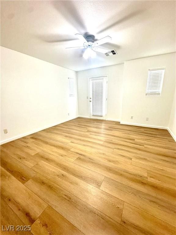 spare room with light wood-style flooring, ceiling fan, and baseboards