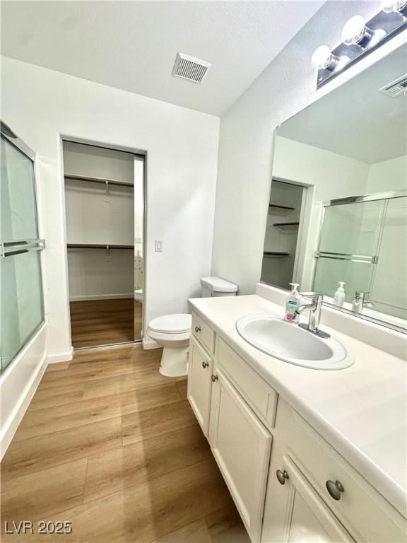 full bathroom with wood finished floors, toilet, vanity, and a spacious closet