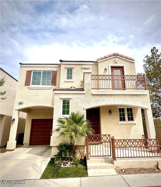 mediterranean / spanish-style home with a balcony, an attached garage, and stucco siding