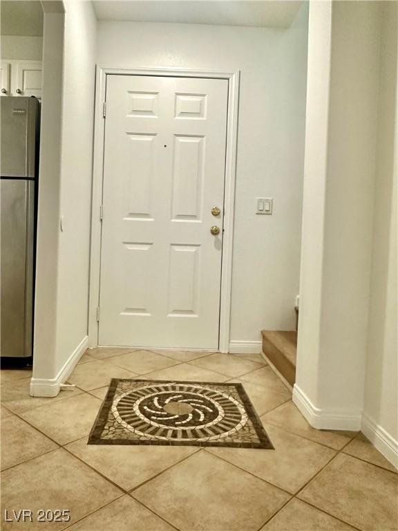 doorway to outside featuring baseboards, light tile patterned floors, and stairway
