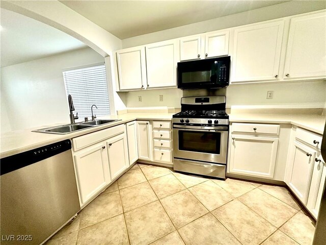 kitchen with stainless steel appliances, a sink, arched walkways, white cabinets, and light tile patterned floors