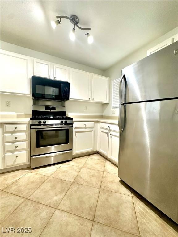 kitchen featuring appliances with stainless steel finishes, light countertops, light tile patterned floors, and white cabinets