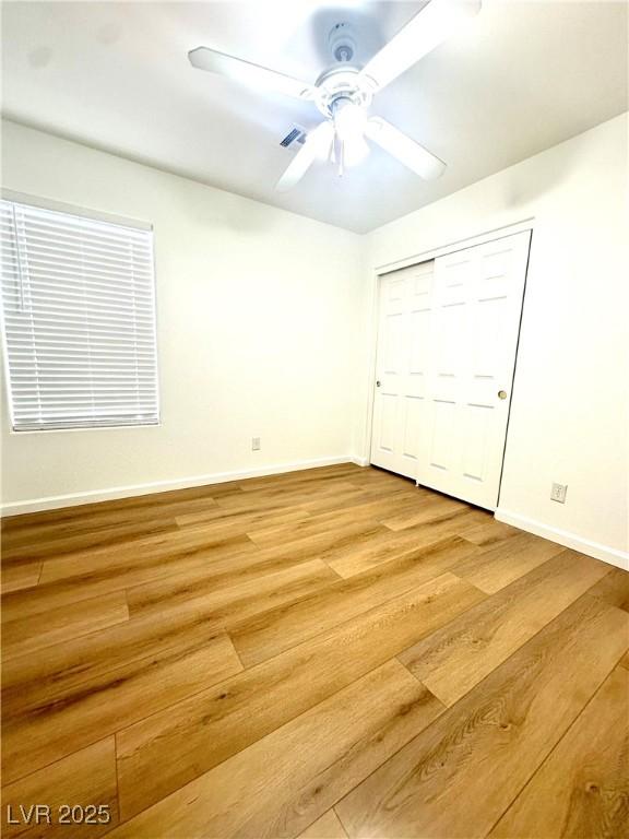 unfurnished bedroom featuring light wood finished floors, baseboards, a closet, and ceiling fan