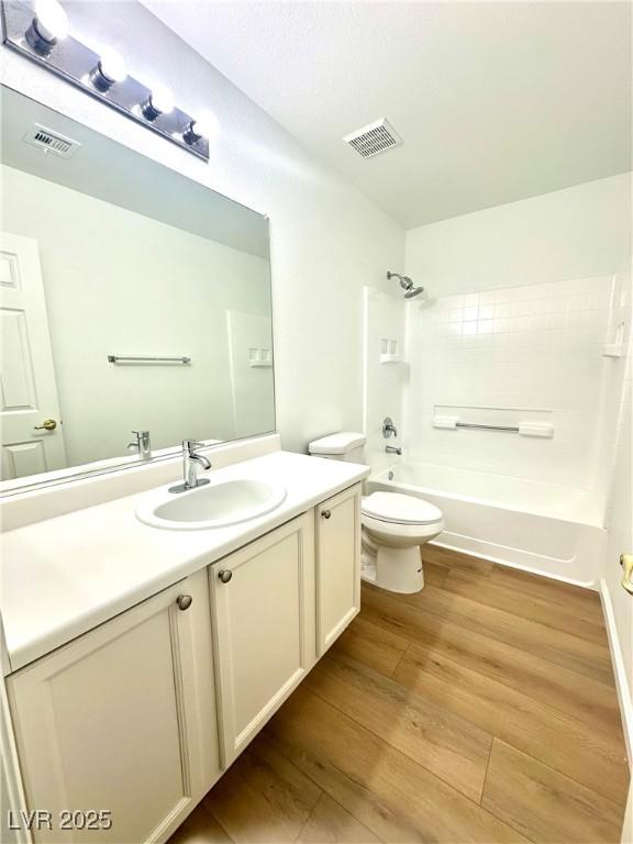 bathroom featuring  shower combination, toilet, wood finished floors, and vanity
