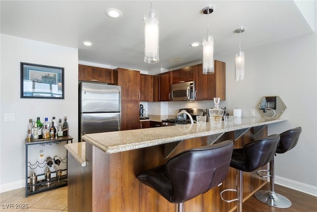 150 Las Vegas Blvd Unit 1608, Las Vegas, NV 89101 - kitchen with appliances with stainless steel finishes, a peninsula, baseboards, a breakfast bar, and light stone countertops