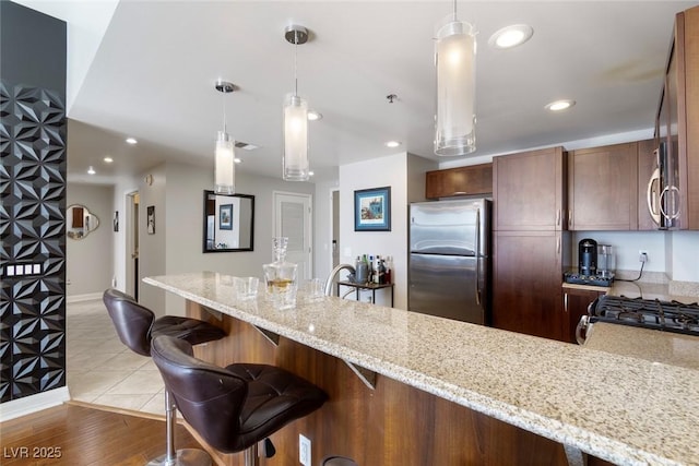 150 Las Vegas Blvd Unit 1608, Las Vegas, NV 89101 - kitchen featuring freestanding refrigerator, hanging light fixtures, a peninsula, light stone countertops, and recessed lighting